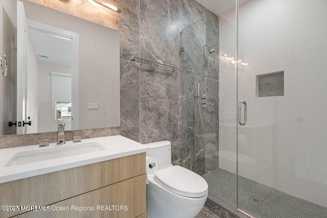 bathroom featuring vanity, toilet, tile walls, and a shower stall