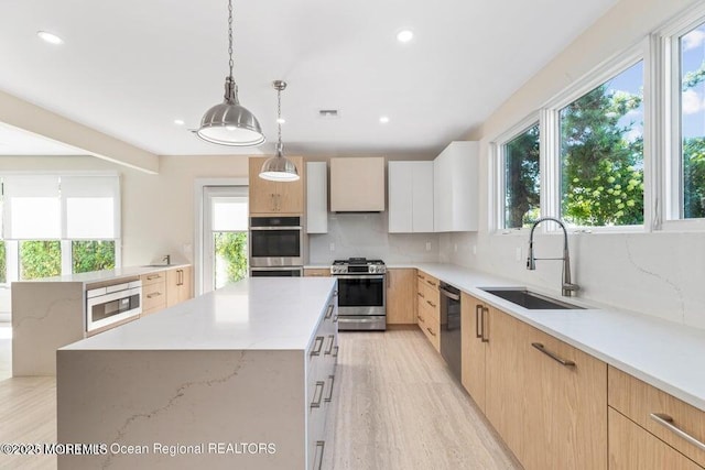 kitchen featuring a center island, stainless steel range with gas stovetop, dishwasher, decorative backsplash, and a sink