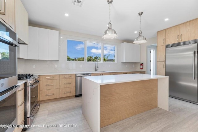 kitchen featuring pendant lighting, a sink, stainless steel appliances, light countertops, and decorative backsplash