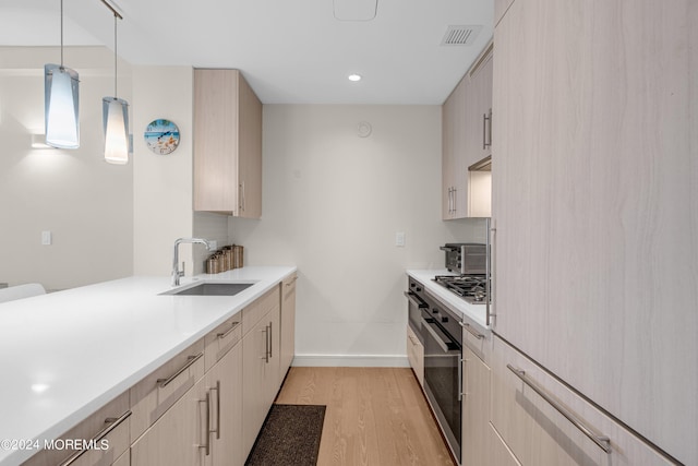 kitchen featuring light wood finished floors, oven, baseboards, light countertops, and a sink