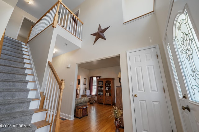 entrance foyer with stairs, wood finished floors, baseboards, and a towering ceiling