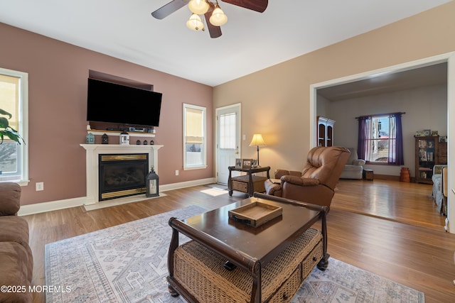 living room featuring plenty of natural light, a fireplace with flush hearth, and wood finished floors