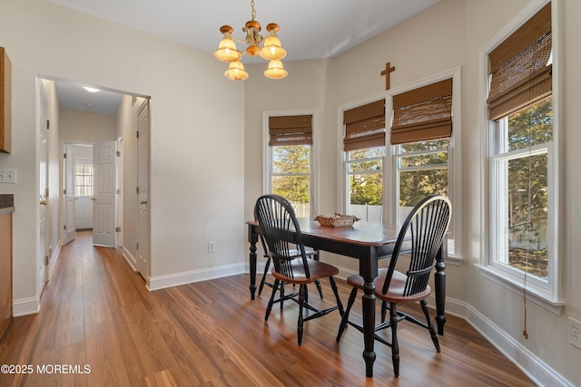 dining area with wood finished floors, baseboards, and a chandelier