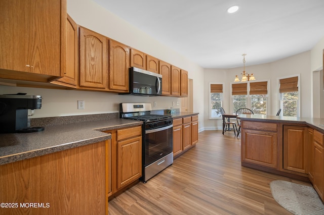 kitchen featuring dark countertops, brown cabinets, appliances with stainless steel finishes, and light wood-type flooring