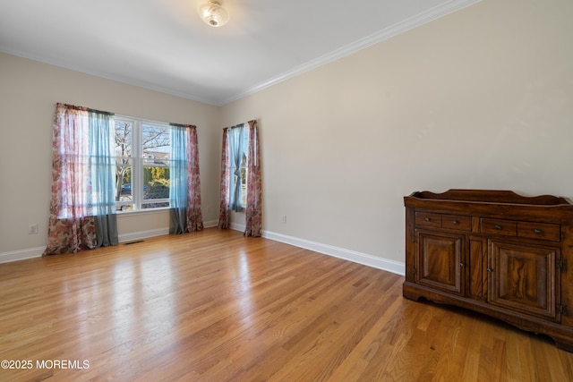 empty room featuring light wood-type flooring, baseboards, and ornamental molding