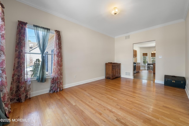 empty room with crown molding, light wood-style flooring, baseboards, and visible vents