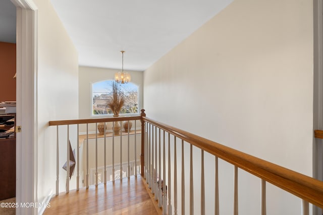 hallway with light wood finished floors and a notable chandelier