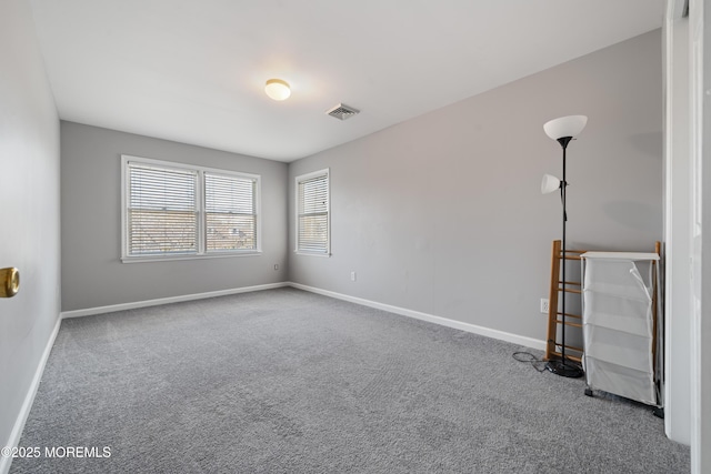 carpeted spare room with visible vents and baseboards