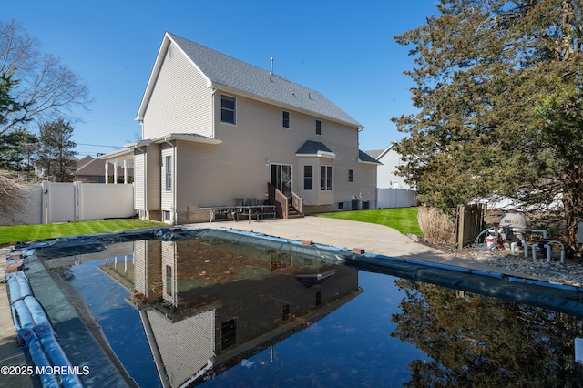 back of house featuring a shingled roof, entry steps, a yard, a fenced backyard, and a patio