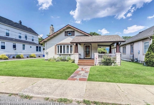 view of front of home featuring covered porch, a chimney, and a front yard