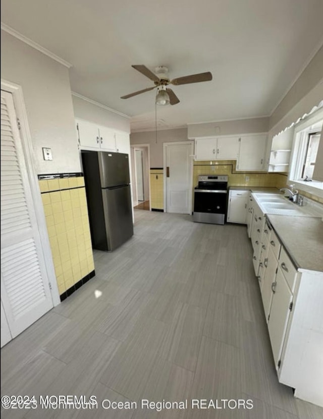 kitchen with a sink, stainless steel range with electric cooktop, white cabinets, and freestanding refrigerator