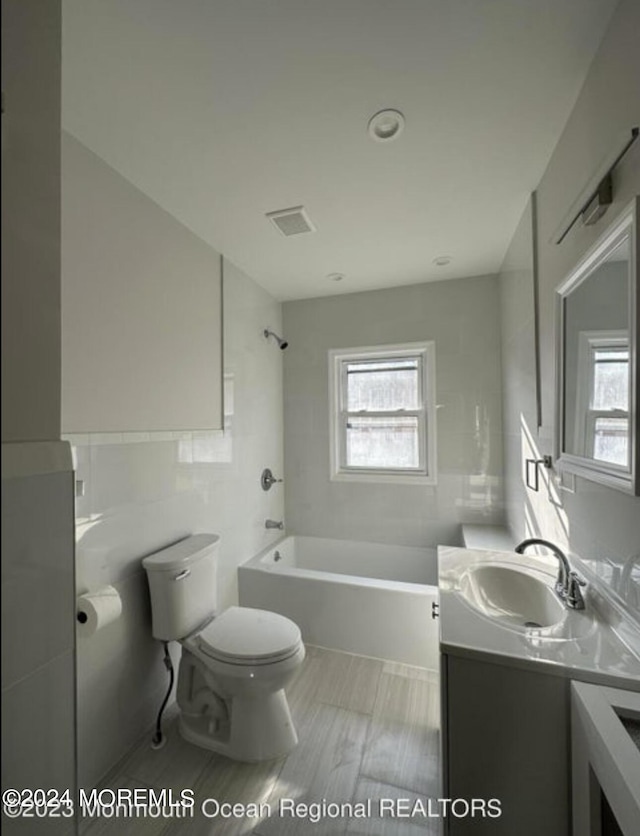 bathroom with plenty of natural light, toilet, tile walls, and vanity