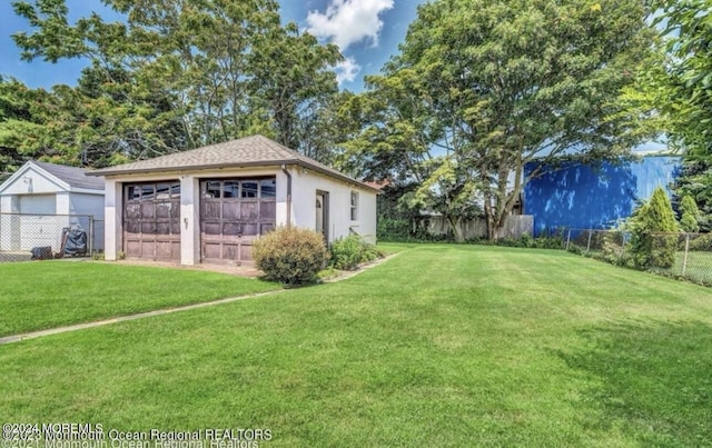 view of yard with a detached garage, an outdoor structure, and fence