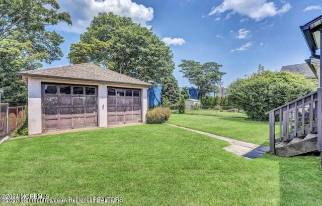 view of yard with an outbuilding, a garage, and fence