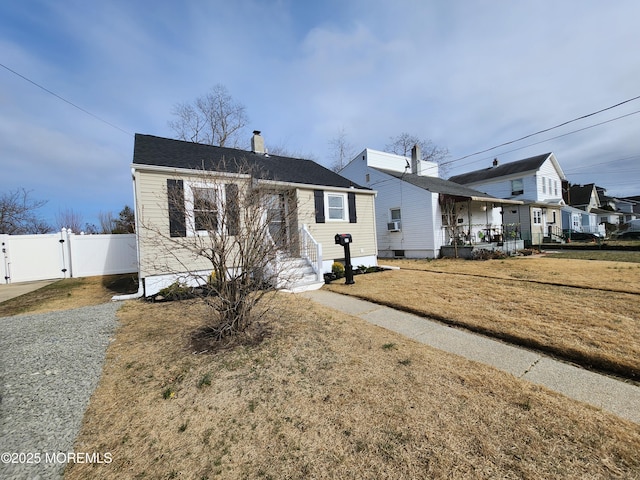 view of front of property with a front lawn, fence, cooling unit, a chimney, and a gate