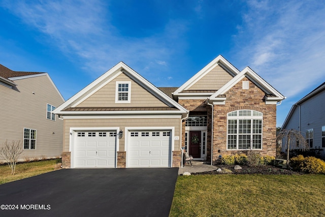 craftsman house with aphalt driveway, an attached garage, stone siding, and a front yard