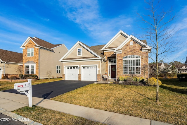 view of front facade featuring a front yard, an attached garage, stone siding, and driveway