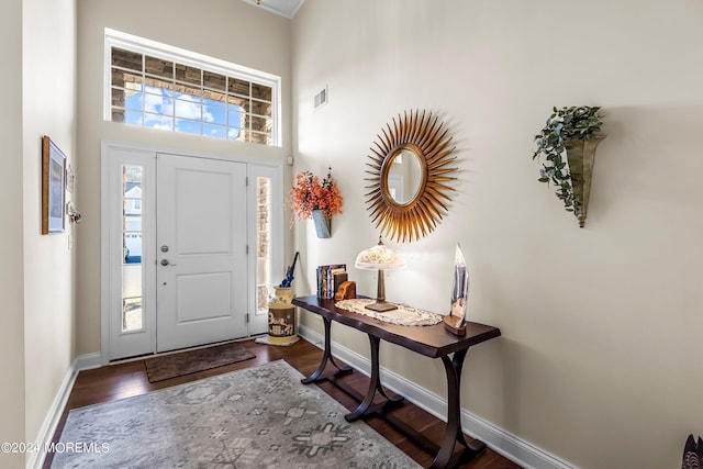 entryway featuring visible vents, baseboards, a high ceiling, and wood finished floors