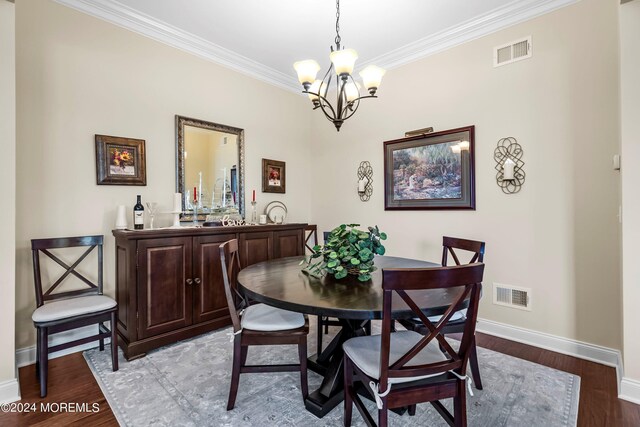 dining space with a notable chandelier, wood finished floors, visible vents, and ornamental molding