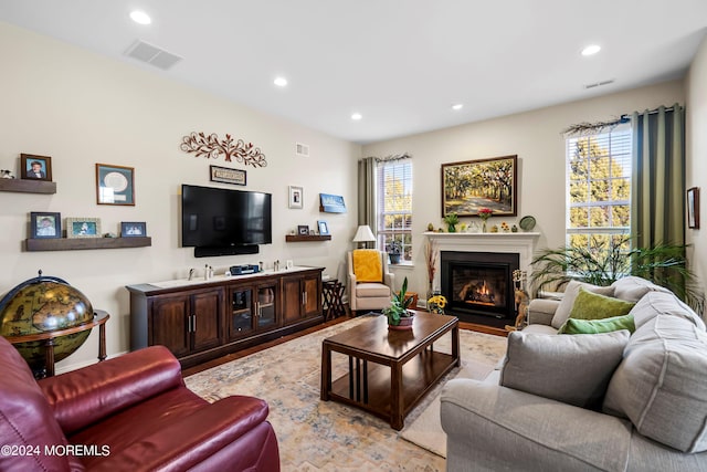 living room with recessed lighting, visible vents, a fireplace with flush hearth, and wood finished floors