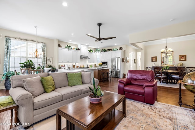 living area featuring ceiling fan with notable chandelier, recessed lighting, and wood finished floors