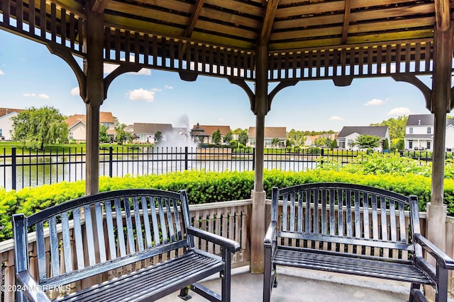 view of patio / terrace featuring a residential view, fence, and a water view