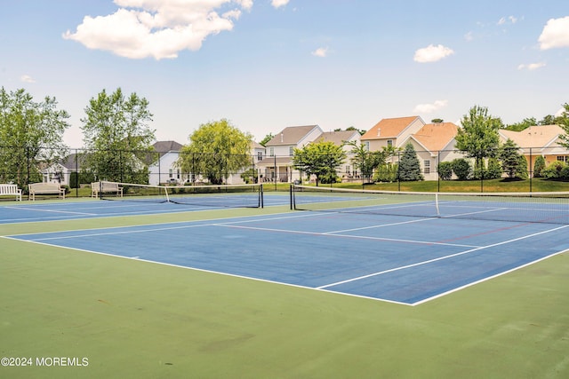 view of tennis court with a residential view and fence