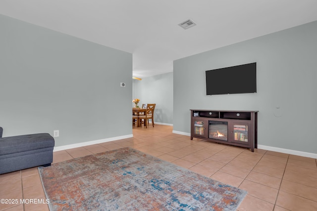 living area with tile patterned floors, visible vents, baseboards, and a glass covered fireplace