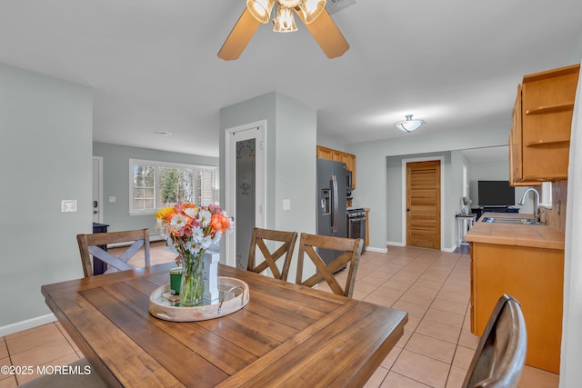 dining space featuring light tile patterned floors, baseboards, and a ceiling fan