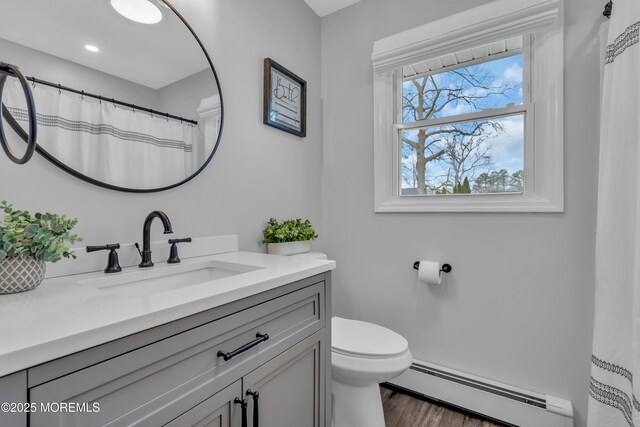 full bathroom with a baseboard heating unit, toilet, wood finished floors, and vanity