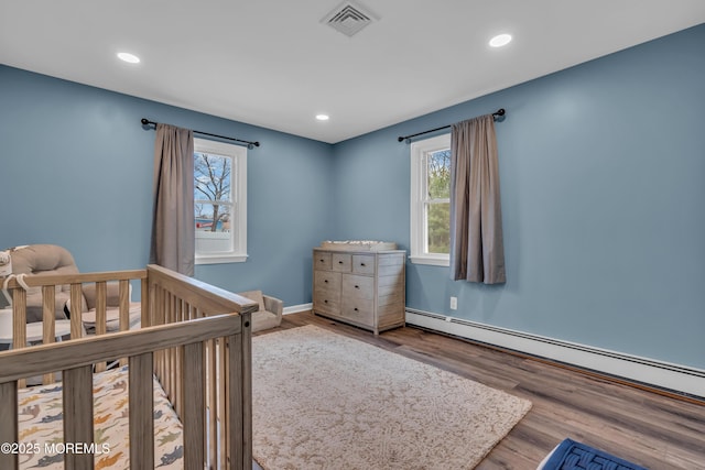 bedroom with visible vents, recessed lighting, a baseboard heating unit, and wood finished floors