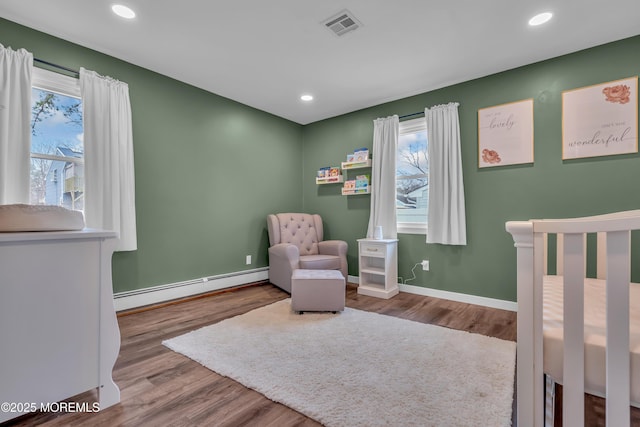 bedroom with multiple windows, wood finished floors, visible vents, and baseboard heating