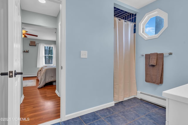 ensuite bathroom featuring tile patterned flooring, a shower with curtain, baseboards, and a baseboard radiator