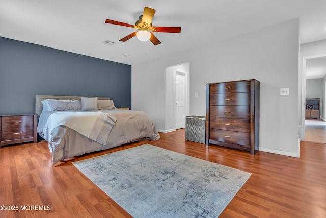 bedroom with visible vents, ceiling fan, baseboards, and wood finished floors