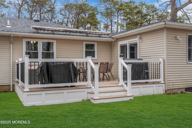 rear view of house with a deck, a shingled roof, and a yard