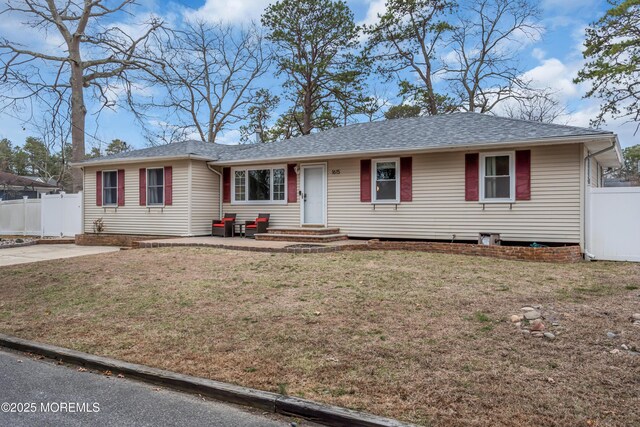 single story home featuring entry steps, a front lawn, fence, and a shingled roof