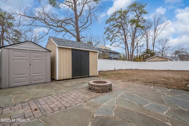 view of patio / terrace with an outdoor structure, a storage unit, a fire pit, and a fenced backyard