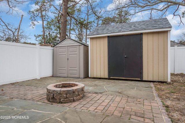 view of shed featuring a fenced backyard and an outdoor fire pit