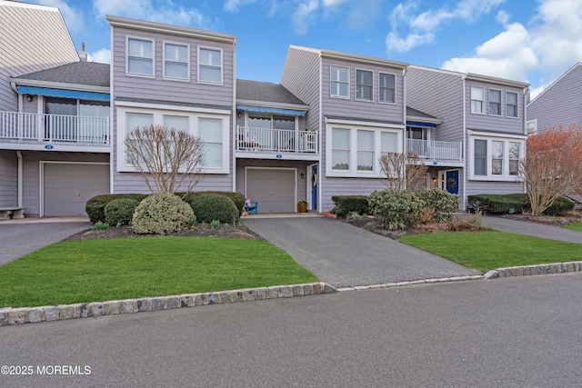 townhome / multi-family property with driveway, a front yard, and a garage