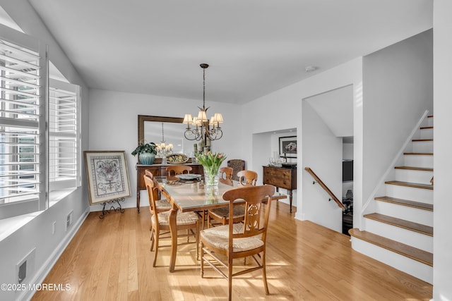 dining space featuring visible vents, a notable chandelier, stairway, and light wood finished floors