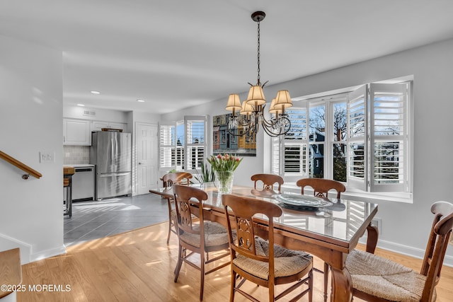 dining area with an inviting chandelier, light wood-style flooring, and plenty of natural light