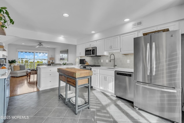 kitchen featuring visible vents, light countertops, decorative backsplash, appliances with stainless steel finishes, and a sink