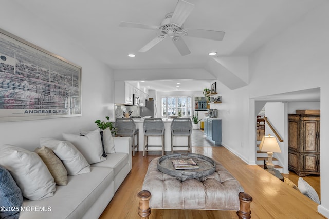 living room featuring a ceiling fan, recessed lighting, light wood-style floors, baseboards, and stairs