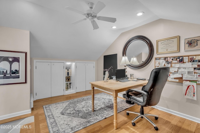 office featuring baseboards, lofted ceiling, light wood-style flooring, and a ceiling fan