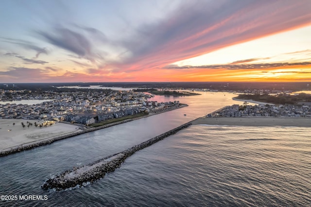 aerial view at dusk featuring a water view