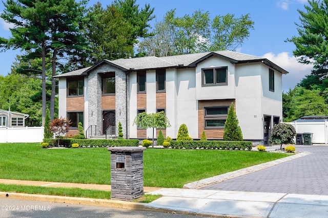 view of front of home with stucco siding, decorative driveway, a front lawn, and fence