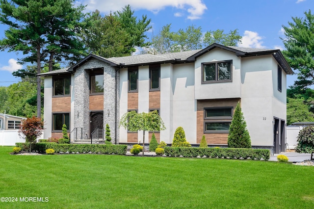 view of front of home featuring a front lawn, roof with shingles, and stucco siding