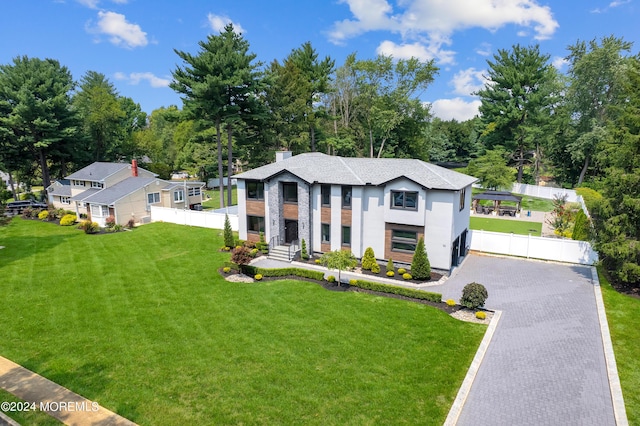 view of front facade featuring fence, stucco siding, a chimney, a front lawn, and decorative driveway