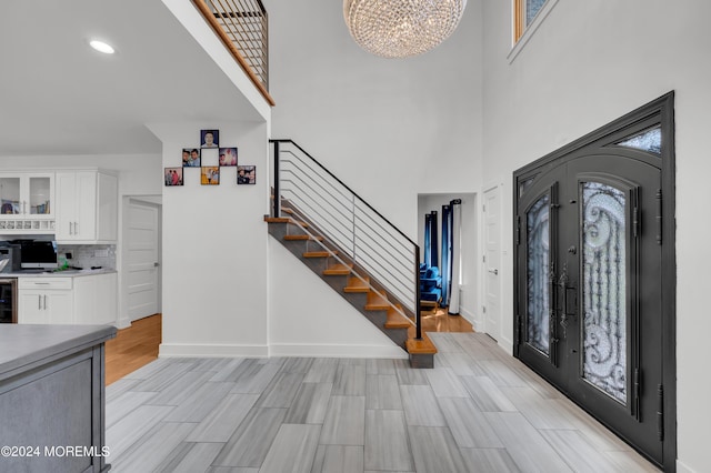 foyer featuring a notable chandelier, french doors, light wood finished floors, baseboards, and stairs