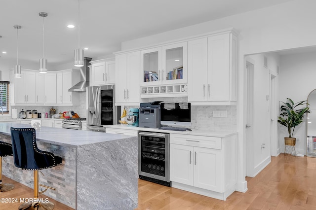 kitchen featuring beverage cooler, white cabinets, appliances with stainless steel finishes, and a breakfast bar